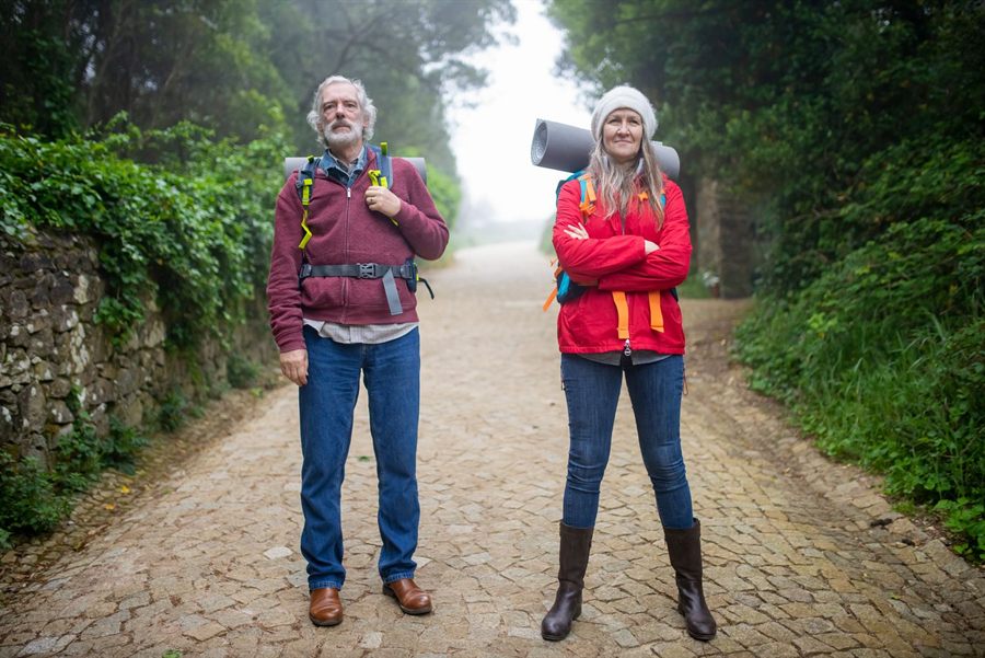 Older couple with daypacks standing on a cobbled path