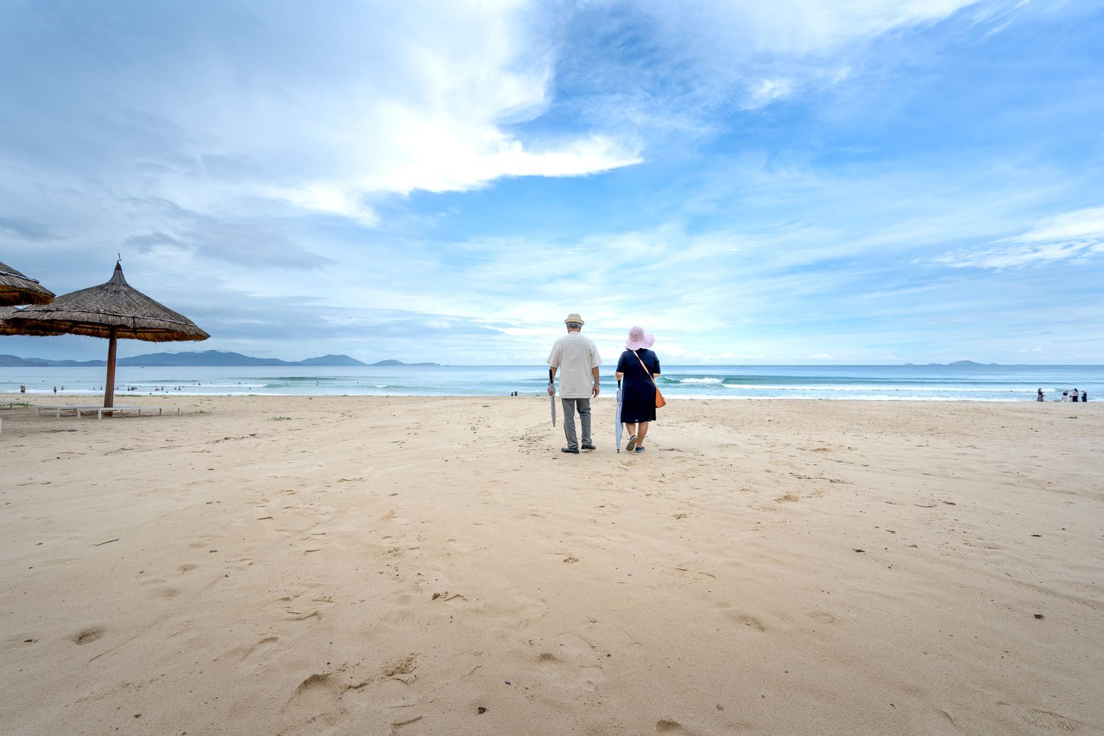 Older couple walking on a wide sandy beach